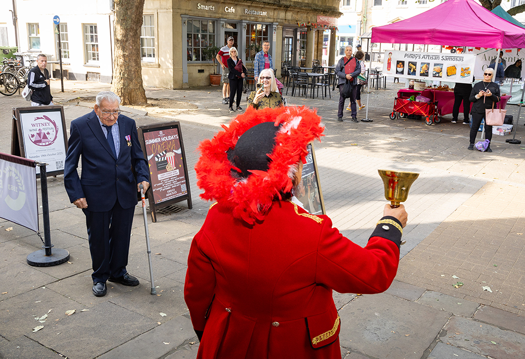 Witney Town Crier (standing right, ringing her bell) announces news regarding a Witney resident, Denis Bishop (Standing to the left of the Crier), who served in the Royal Air Force during the Second World War, and now celebrates his 100th birthday.